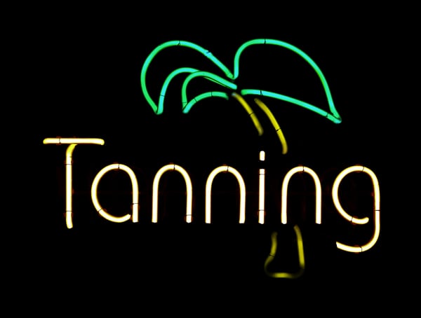 Neon sign in window of tanning salon, isolated on black